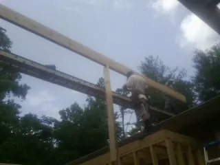 Carpenter setting a ridge beam over a new addition frame — Ice Dam Removal by Roofing Brothers in Grand Coteau
