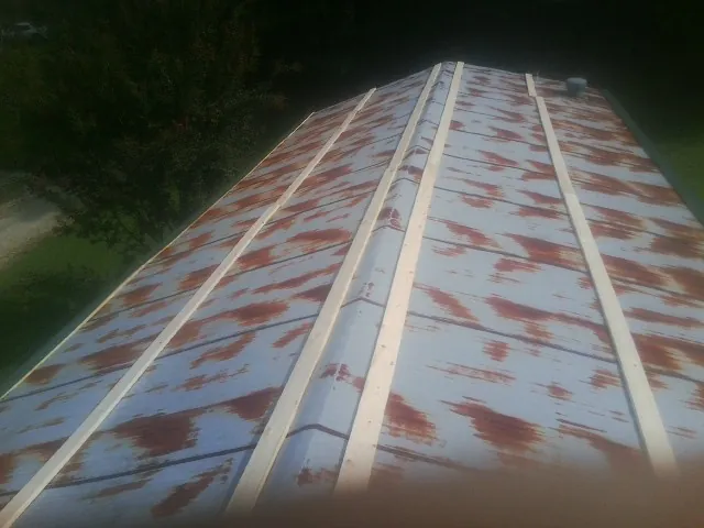Rusted metal roof panels with new wood purlins before replacement — Storm Damage Roof Repair in Grand Coteau by Roofing Brothers