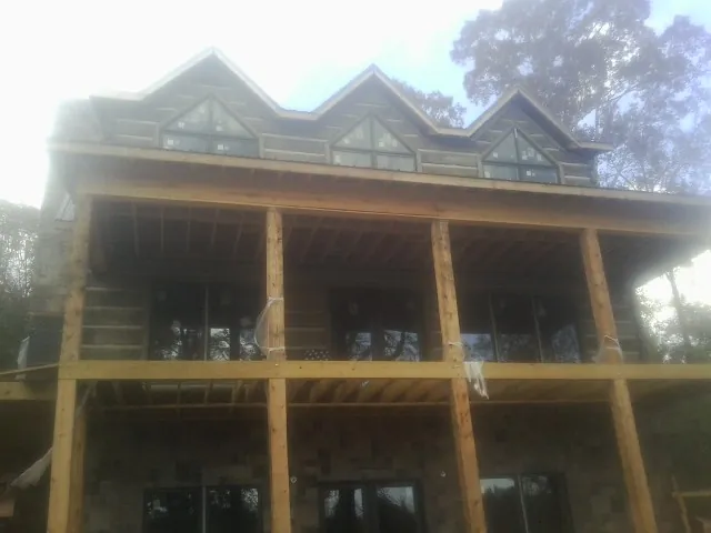 Dormers and porch framing on a large log home under construction — Roof Coating work by our crew in Grand Coteau