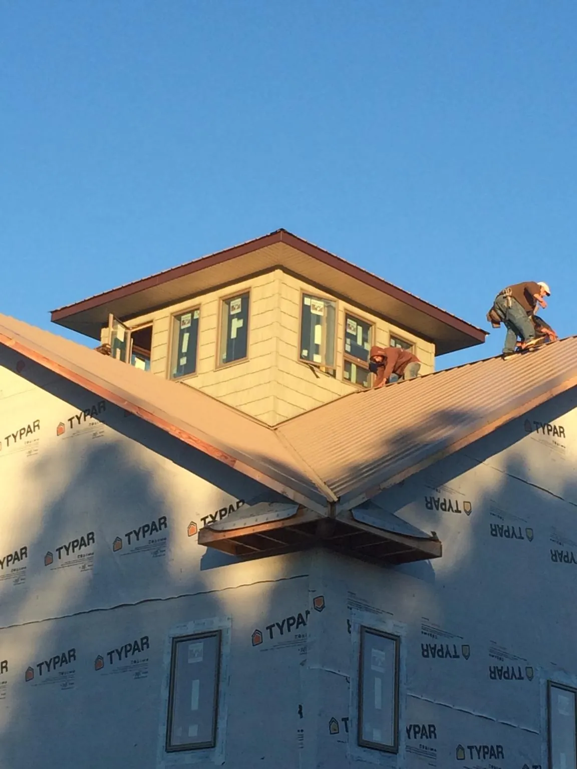 Roofers working around a rooftop cupola on a new metal roof at sunset — Roof Waterproofing in Grand Coteau by Roofing Brothers